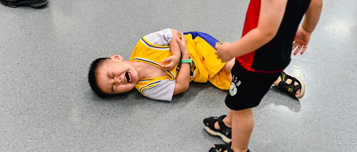 enfant au sol qui pleure pres d'un enfant debout