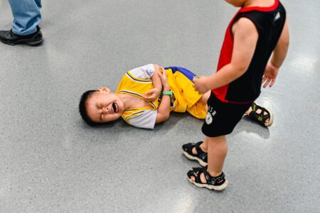enfant au sol qui pleure pres d'un enfant debout